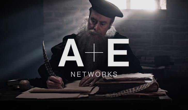 A+E Networks logo over a scribe writing on a scroll.
